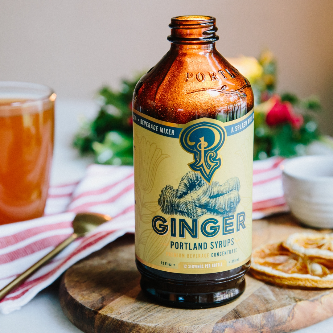 Bottle of Portland Syrups ginger syrup on a wooden cutting board with a blurred background