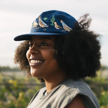 Woman wearing a blue cap with bird designs outdoors