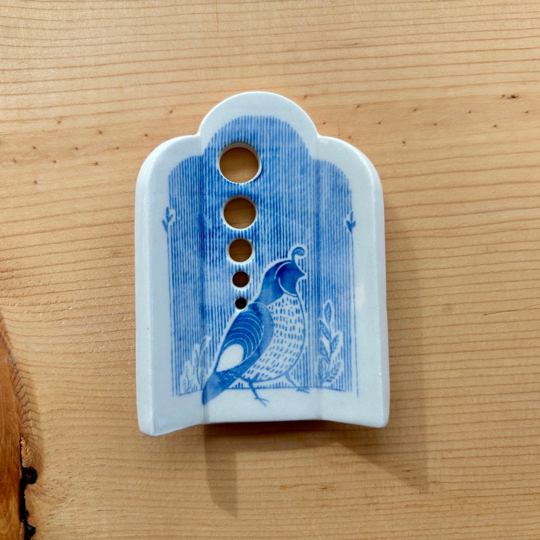 a ceramic herb stripper with 5 different sized holes to pull herbs through to remove the leaves, blue stripes and a quail on the bottom