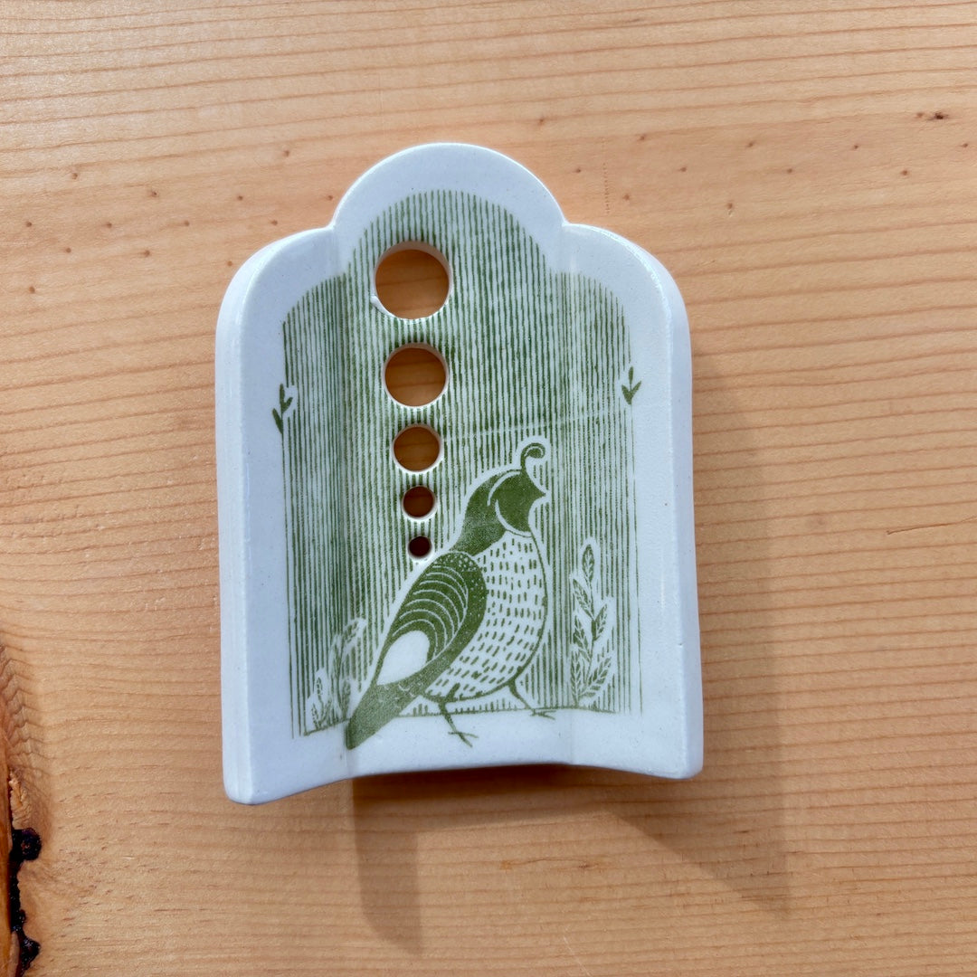 a ceramic herb stripper with 5 different sized holes to pull herbs through to remove the leaves, green stripes and a quail on the bottom