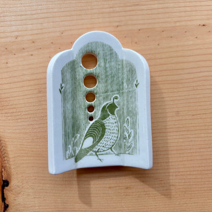 a ceramic herb stripper with 5 different sized holes to pull herbs through to remove the leaves, green stripes and a quail on the bottom