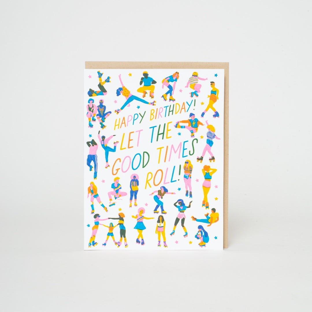 A birthday greeting card with a kraft paper envelope, featuring a white background decorated with colorful illustrations of people roller skating and the text 'HAPPY BIRTHDAY! LET THE GOOD TIMES ROLL!'.
