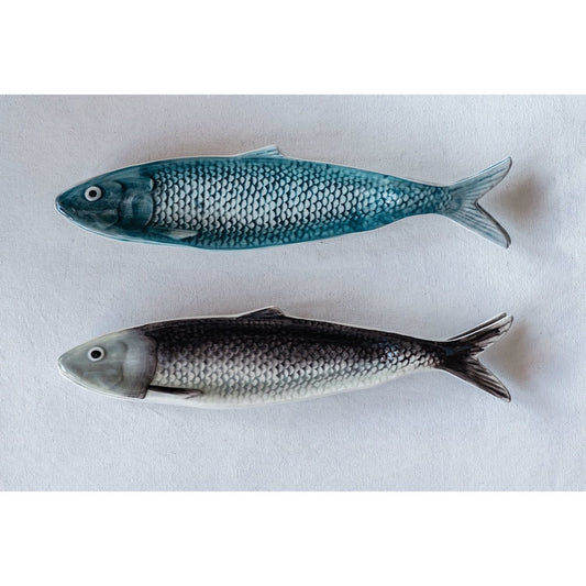 Two sardine shaped plates, one blue and one gray, on a white background