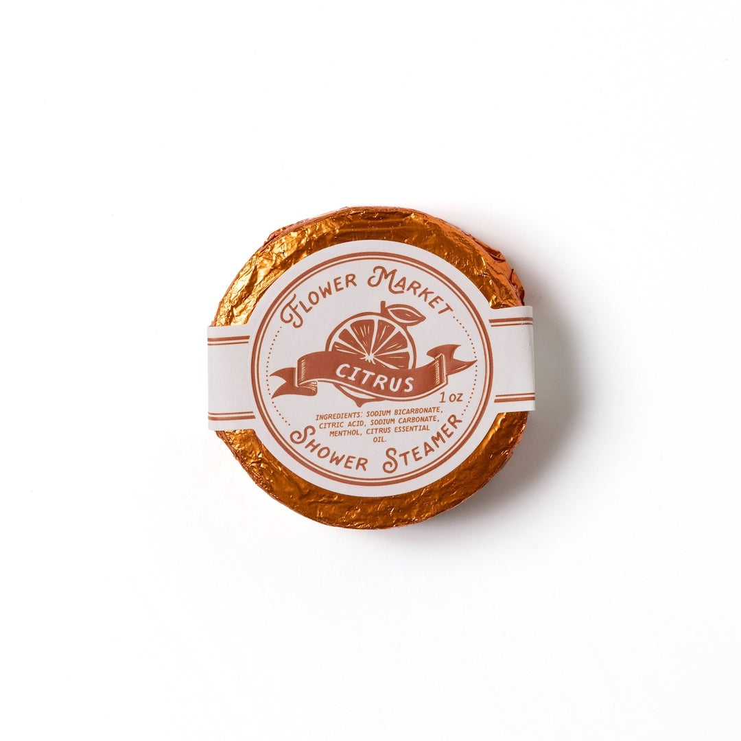 Round citrus scented shower steamer with 'Flower Market' branding on a white background
