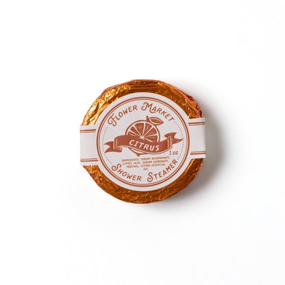 Round citrus scented shower steamer with 'Flower Market' branding on a white background