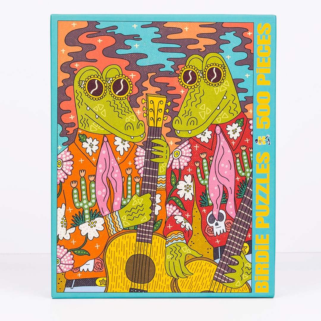 A colorful jigsaw puzzle box featuring two cartoon alligators playing guitars, with the text 'BIRDIE PUZZLES 500 PIECES' on the right side, shown against a plain white background.