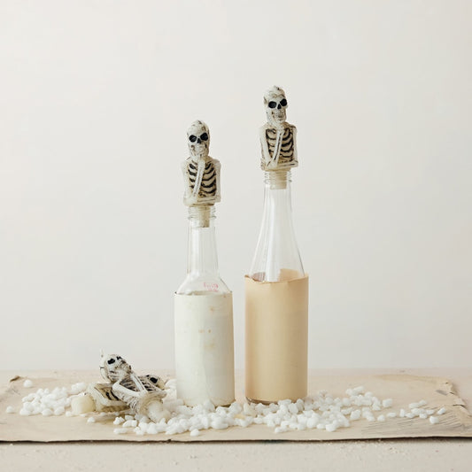 Two bottles with skeleton candles in the tops on a white background