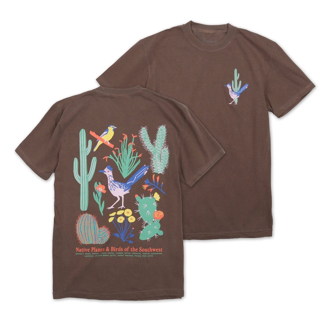 Two brown short-sleeve T-shirts shown on a white background, with the front and back views overlapping. The back shirt features a large colorful desert illustration with cacti, birds, and text reading 'Native Plants & Birds of the Southwest.