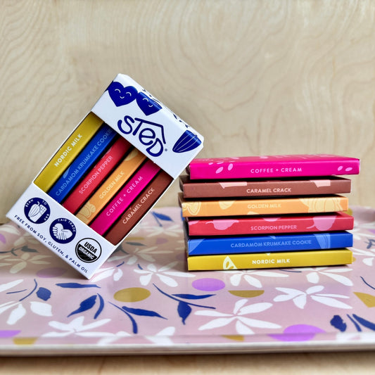 Packaged mini chocolate bars with colorful labels on a floral-patterned surface