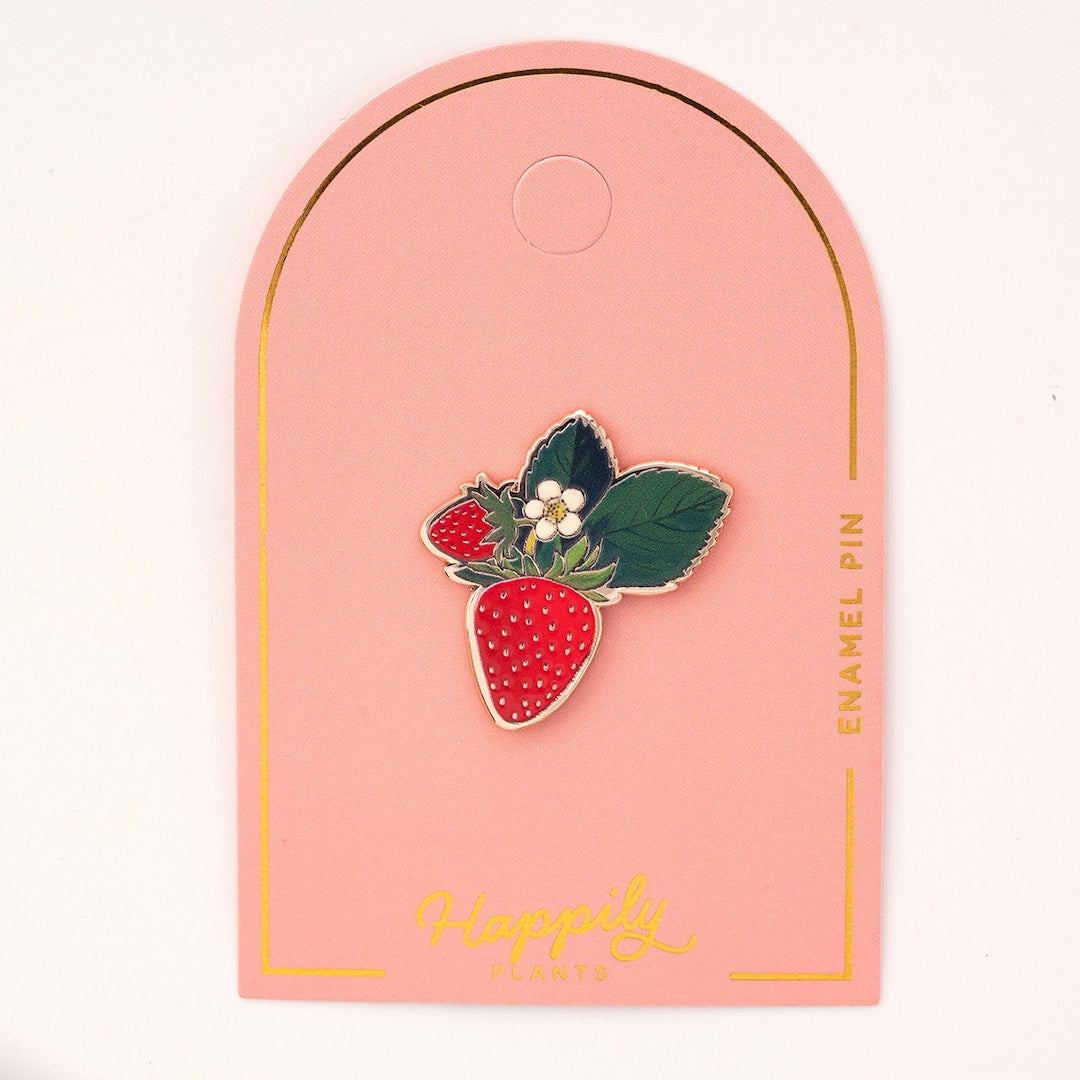 Strawberry enamel pin on a pink card 