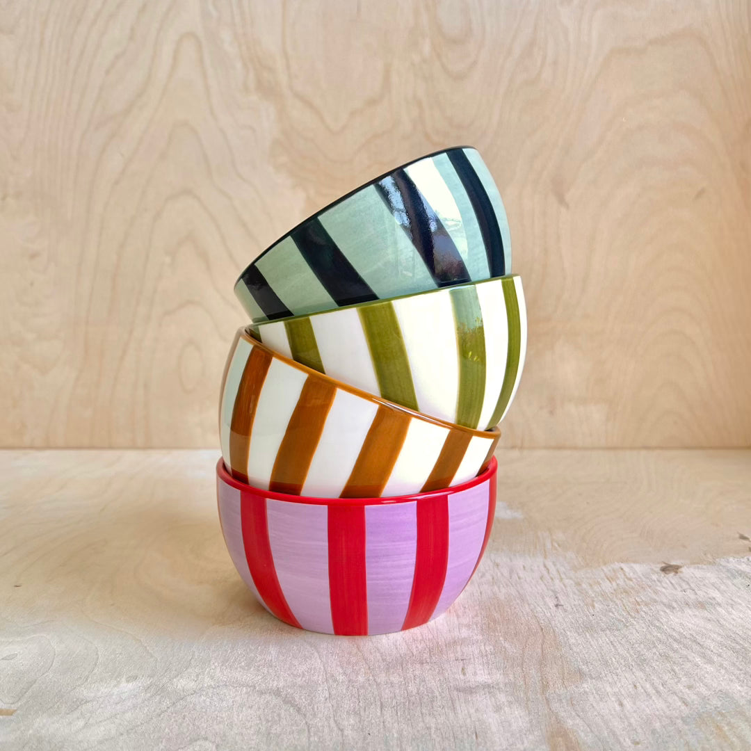 Stack of colorful striped ceramic bowls on a wooden surface