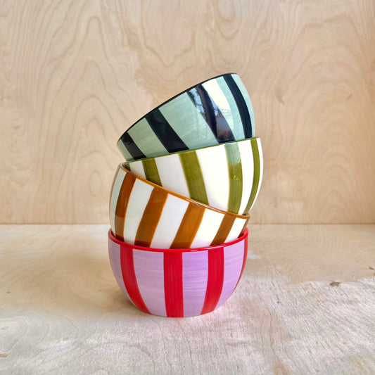 Stack of colorful striped ceramic bowls on a wooden surface