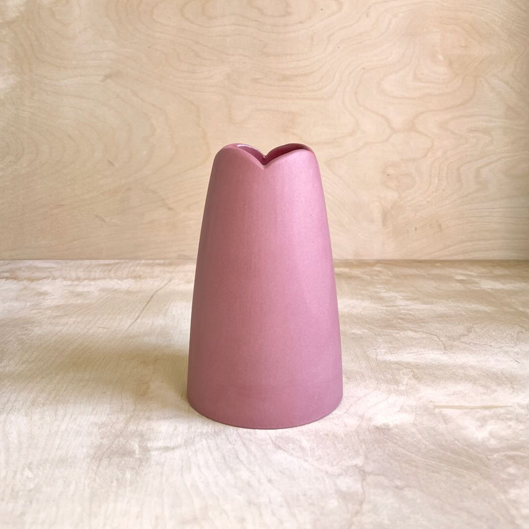 cranberry colored vase on a light wooden surface