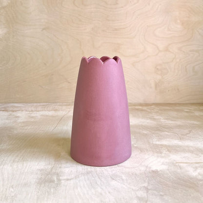 cranberry colored ceramic vase on a light wooden surface