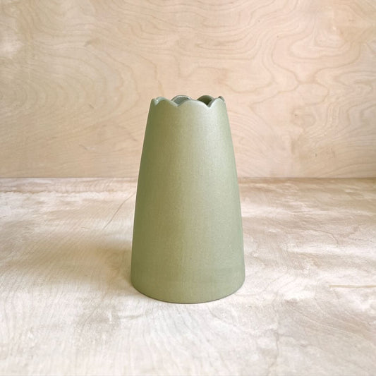 Green ceramic vase on a light wooden surface