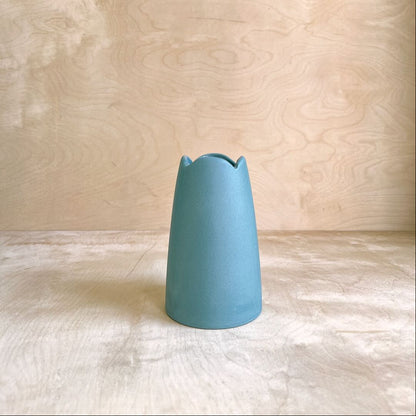 Blue ceramic vase on a textured surface with a neutral background
