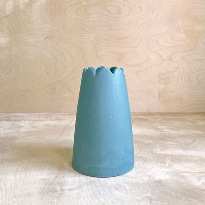 Blue ceramic vase on a light wooden surface with a wooden background