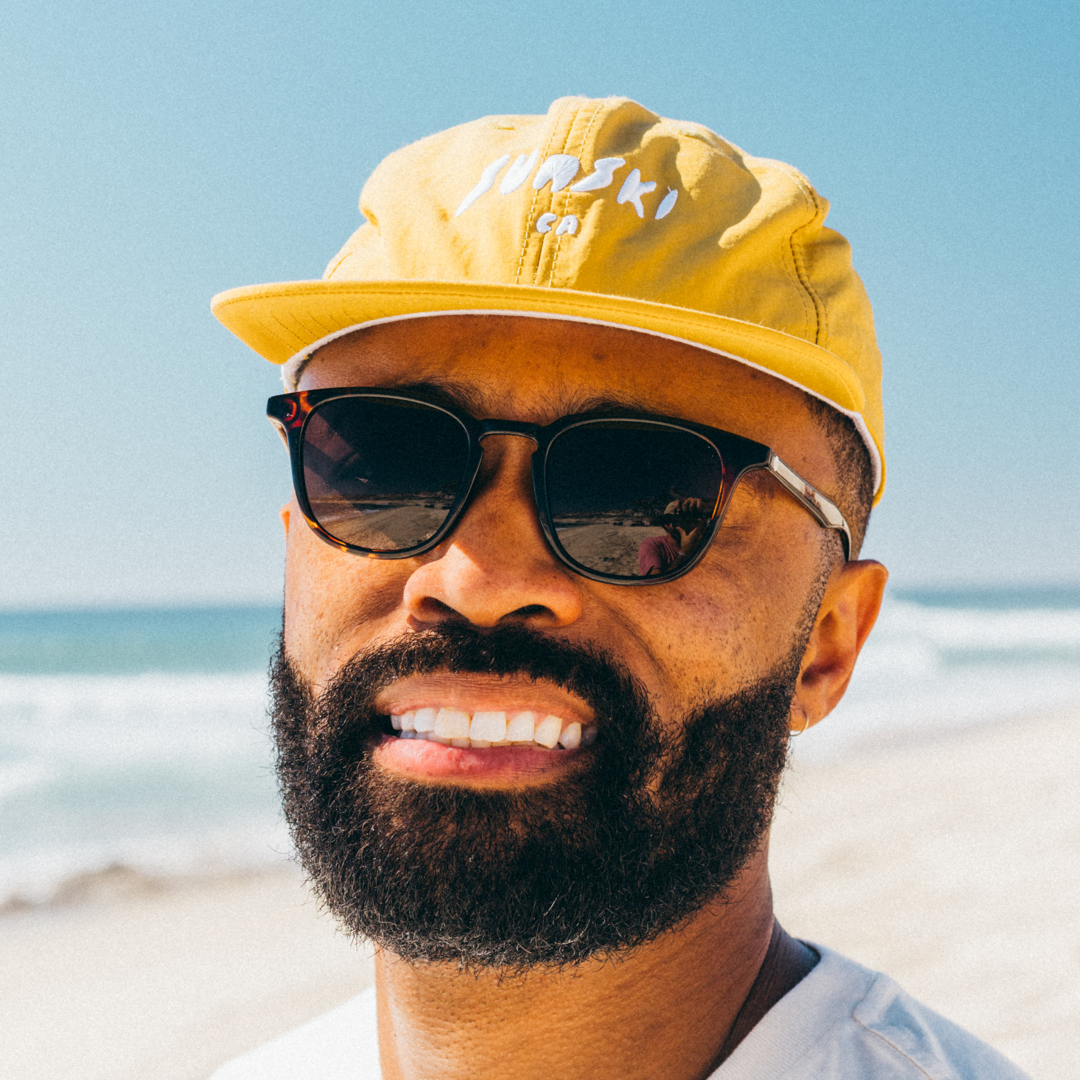 Man wearing a yellow cap and sunglasses on a beach
