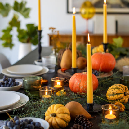 table setting with pumpkins, candles, and greenery.