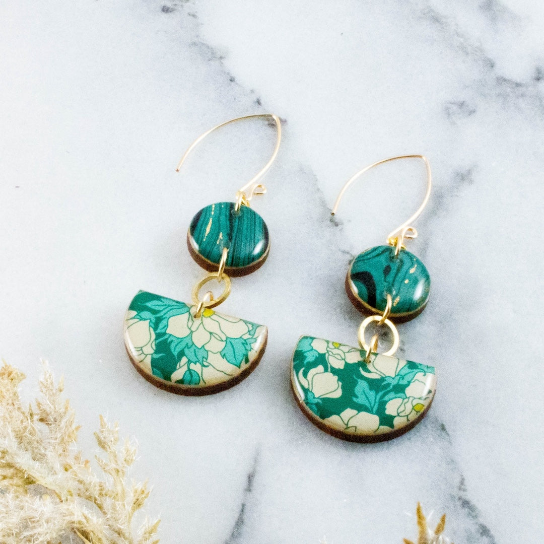 Teal floral earrings on a marble surface 