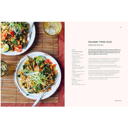 An open cookbook spread showing a recipe for Railway Fried Rice. The left page features a photograph of two plates of prepared fried rice with lime wedges on a bamboo mat, and the right page contains the recipe text on a pale pink background.