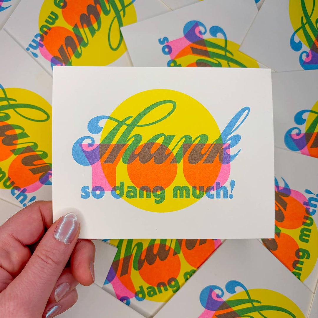 Colorful card with 'Thank so dang much!' text held by a hand, surrounded by similar cards.