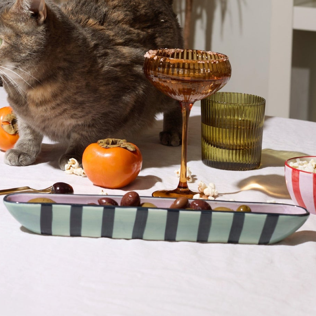Light and dark blue striped olive boat filled with olives on a table scape 