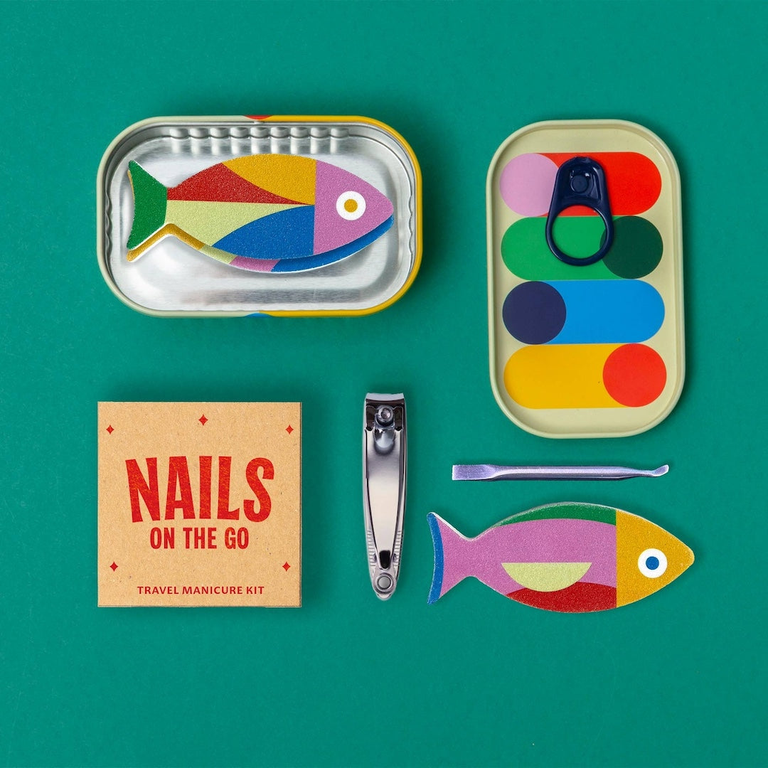 Travel manicure kit with fish shaped nail files, a cuticle stick, and travel sized nail clipper. Shown with the tin it comes packed in