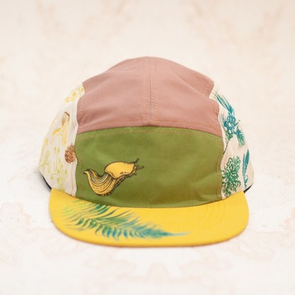Colorful cap with floral patterns and a banana slug and a yellow base on a light background