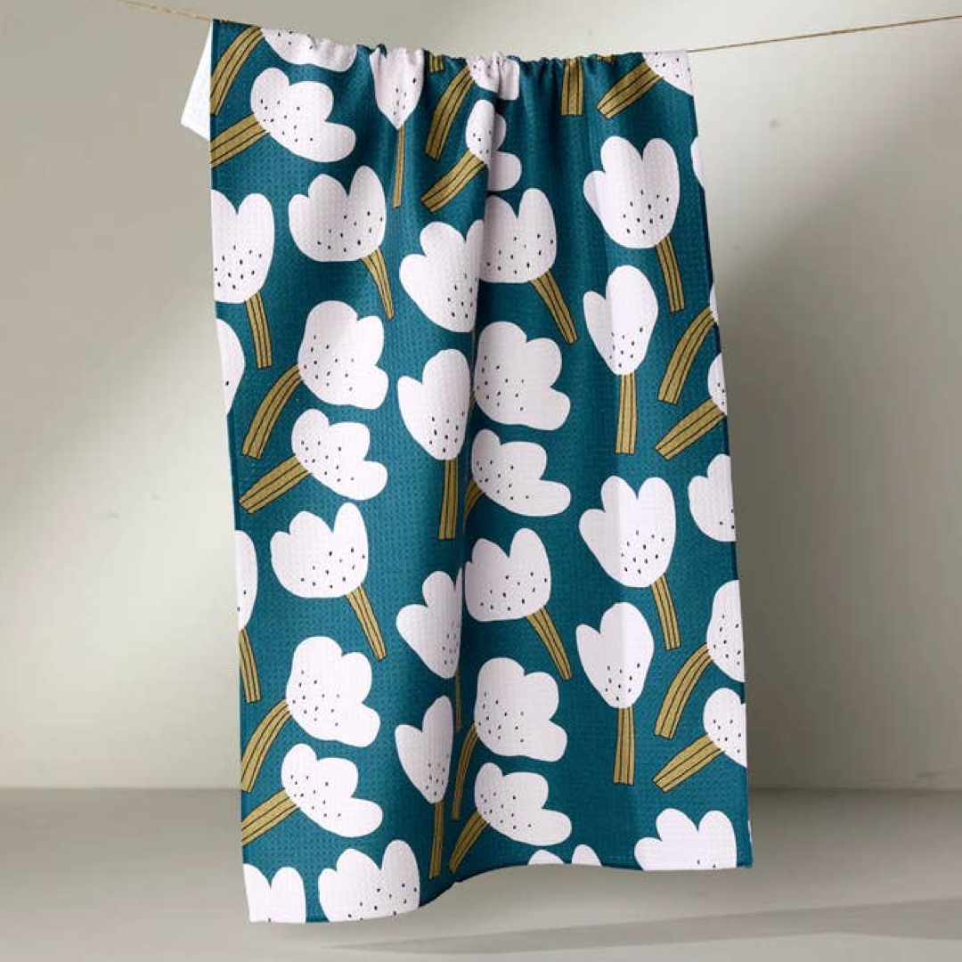 Floral patterned dishtowel with white flowers on a teal background