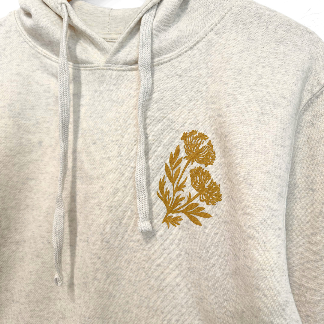 heather white hoodie with a gold floral design on the chest against a white background