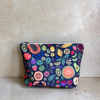 Dark fruit patterned pouch on a light wooden surface