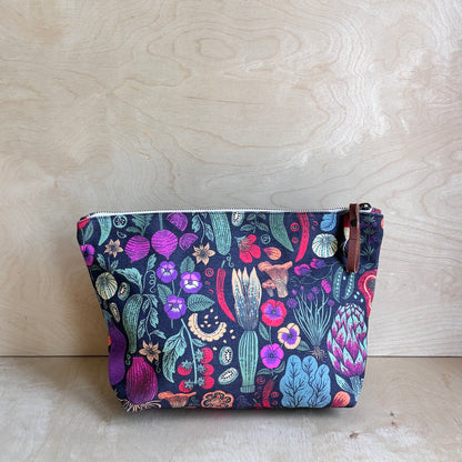 Dark veggie and floral patterned pouch on a wooden surface