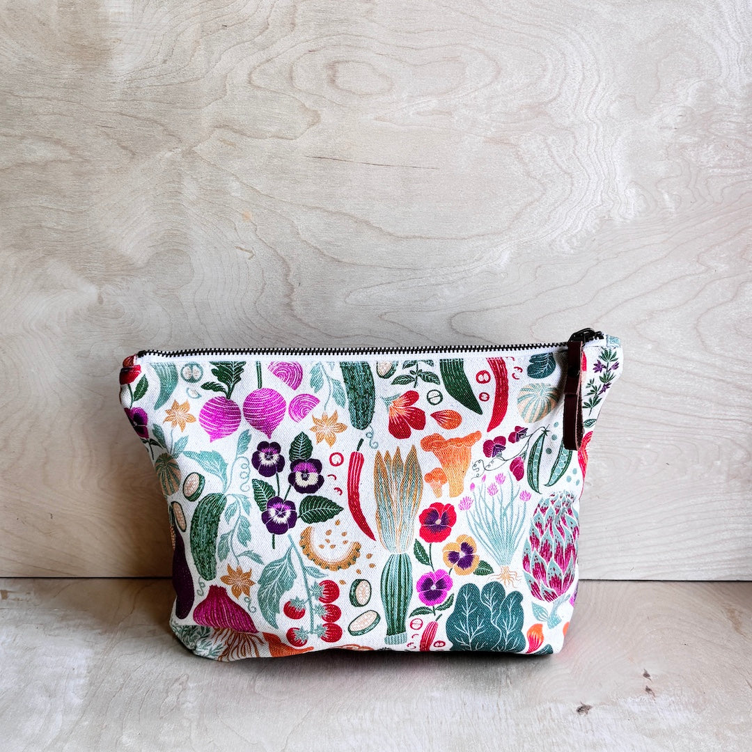 White veggie and floral patterned pouch on a wooden surface
