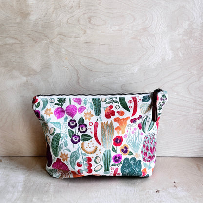 White veggie and floral patterned pouch on a wooden surface