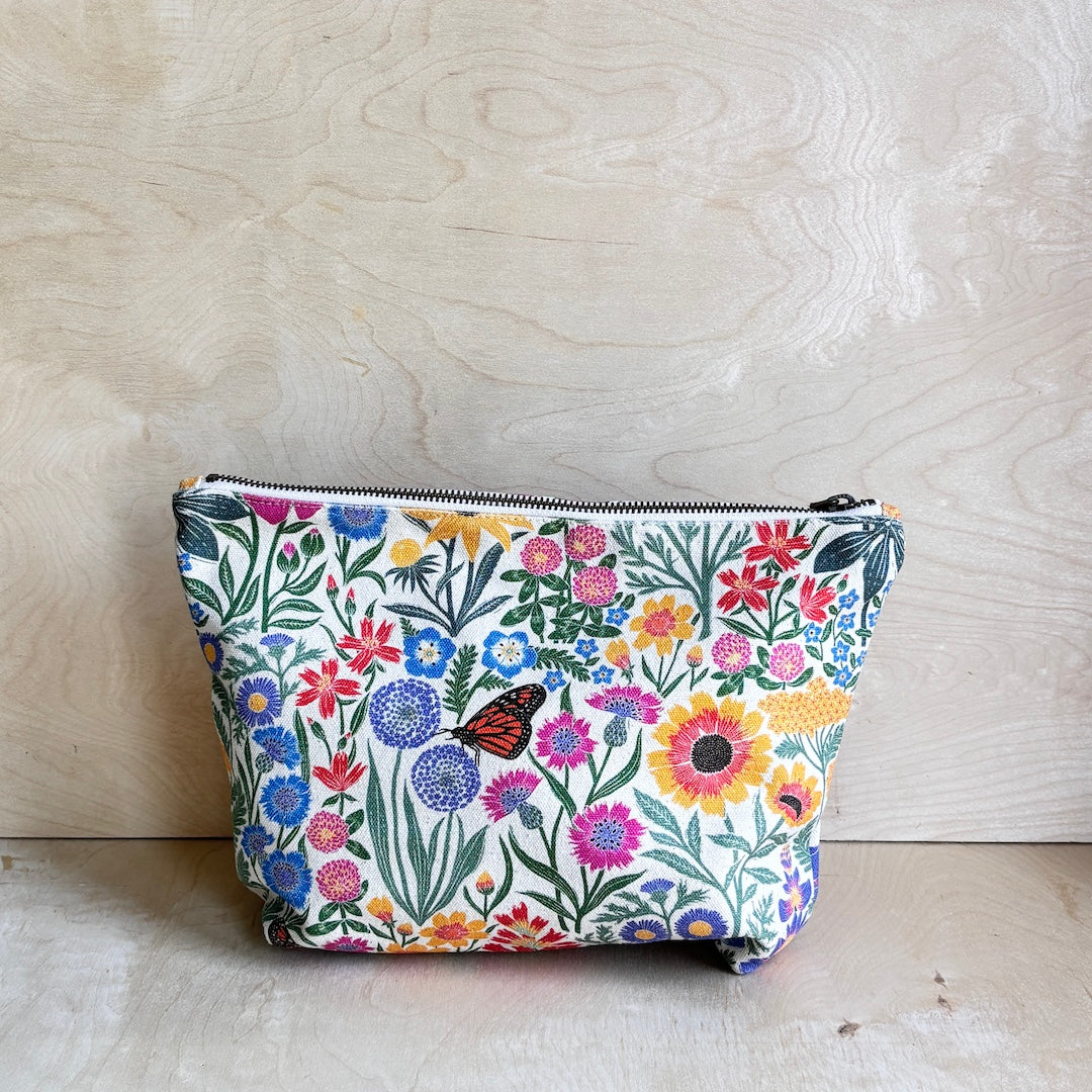 White Floral-patterned pouch with a zipper on a wooden surface